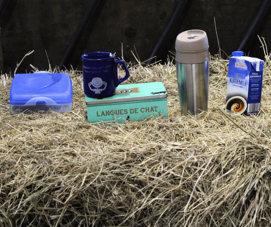 Sfeerbeeld in de stal met koffiebeker en broodtrommel